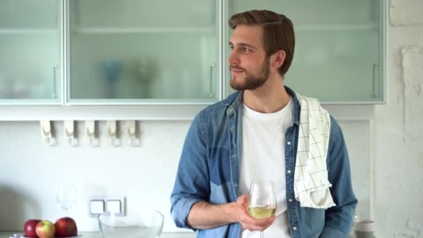 긴장 한 젊은이는 식탁 근처에서 신선 한 재료를 주방에 넣은 포도주를 마시고 있다 — 비디오