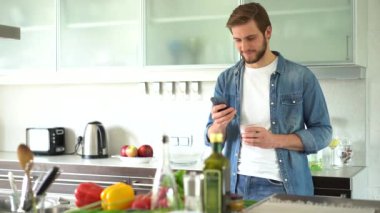 Evde akıllı telefon kullanan çekici bir adam mesaj gönderiyor.