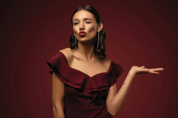 Vacker modell flicka med elegant frisyr i röd klänning visar produkten. Vacker flicka pekar åt sidan — Stockfoto