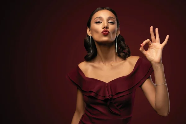 Hermosa chica modelo con peinado elegante en vestido rojo que muestra signo ok. Mujer con labios rojos y uñas. —  Fotos de Stock