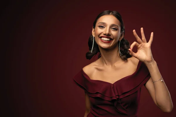 Menina modelo bonita com penteado elegante em vestido vermelho mostrando sinal ok. Mulher com lábios e unhas vermelhas. — Fotografia de Stock