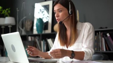 Kendine güvenen kadın kablosuz kulaklık takıyor. Web kamerasıyla konuşuyor. Kadın profesyonel şirket temsilcisi kameraya konuşuyor.
