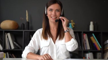 Kendine güvenen kadın kablosuz kulaklık takıyor. Web kamerasıyla konuşuyor. Kadın profesyonel şirket temsilcisi kameraya konuşuyor.