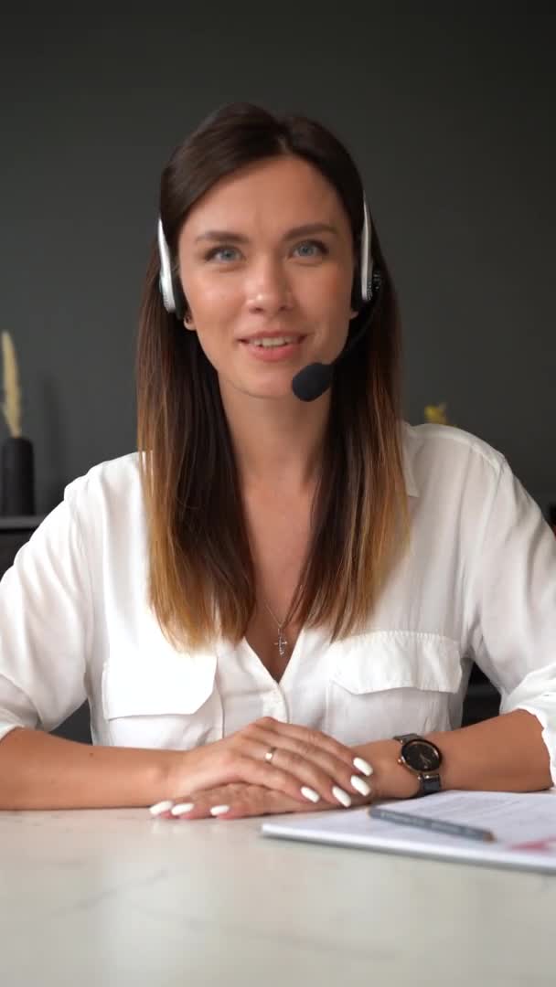 Вертикальний знімок впевненої жінки в бездротовій гарнітурі, що розмовляє з веб-камерою, представниця жіночої компанії розмовляє з камерою — стокове відео
