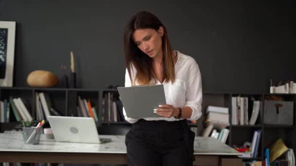 Mujer europea adulta joven y sonriente confiada mirando la cámara de pie en la oficina, posando para un retrato de cerca en interiores — Vídeos de Stock