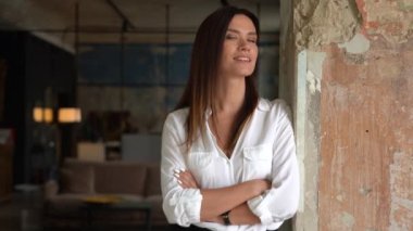 Kendinden emin gülümseyen genç Avrupalı kadın ofiste duran kameraya bakıyor, kapalı alanda portre için poz veriyor.