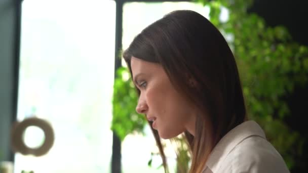 Självsäker leende ung vuxen europeisk kvinna tittar på kameran på kontoret, poserar för närbild porträtt inomhus — Stockvideo