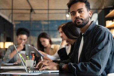 Ofisteki toplantı odasında meslektaşlarına karşı oturan kendinden emin, melez iş adamının portresi..