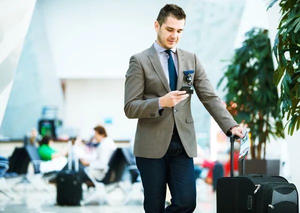 Businessman at airport with smartphone — Stock Photo, Image