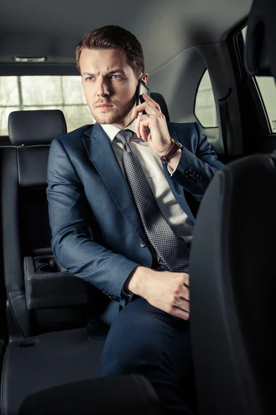 Affärsman i bilen med mobiltelefon — Stockfoto