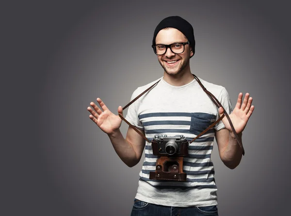 Young man with camera over grey background — Stock Photo, Image