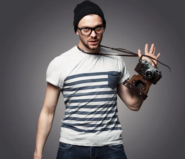 Young man with camera over grey background — Stock Photo, Image