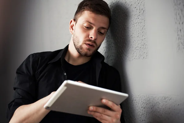 Man met tablet door de muur — Stockfoto