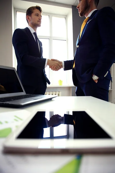 Tablet computador com homens de negócios handshaking — Fotografia de Stock