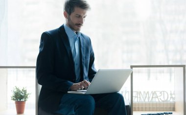 Businessman using laptop computer in office. Happy middle aged man, entrepreneur, small business owner working online