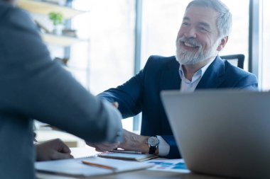 Grup yönetim kurulu toplantısında el sıkışan mutlu iş adamları. Profesyonel iş yürütme liderleri şirket ortaklığı el sıkışma konseptini başarılı bir şekilde imzaladılar.