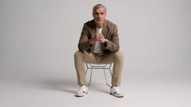 Mutlu orta yaşlı iş adamı beyaz arka planda izole bir şekilde sandalyede oturuyor. 40 'lı yaşlarda mutlu bir iş adamı. Tam vücut fotoğrafı..