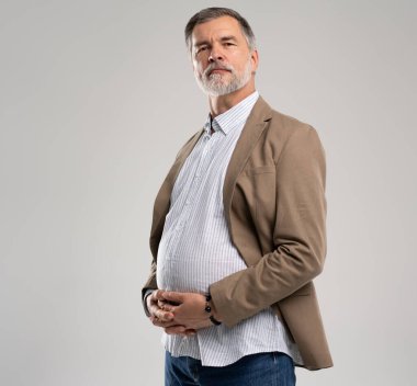 Gülümseyen olgun, kilolu bir adam beyaz arka planda yalnız poz veriyor.