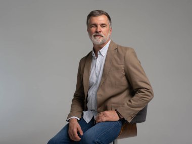 Mutlu, zarif, olgun bir adamın beyaz arka planda oturup gülüşünün tüm vücudu.