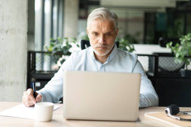 Gülümseyen 40 'lı yılların erkek muhasebeci analisti elinde belgeler, dizüstü bilgisayarda çalışıyor online ticaret pazarı teknolojisi araştırmaları yapıyor. Ofisinde evrak işleriyle uğraşan odaklanmış bir işadamı.