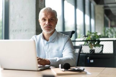 Mutlu Avrupalı iş adamı CEO 'su bilgisayar kullanıyor, daktilo kullanıyor, modern ofiste çalışıyor, çevrimiçi veri pazarı analizi yapıyor, bilgisayar kopyalama alanı olan dizüstü bilgisayara bakarak teknoloji stratejisi planlıyor.