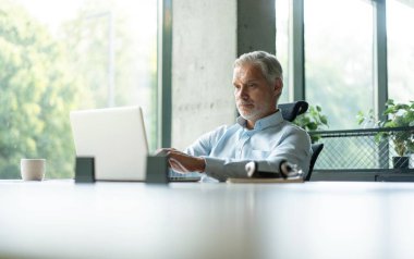 Gülümseyen işadamı müşteriyle konuşurken kulaklık kullanıyor. Kulaklıktaki teknik destek müdürü bir müşteriye danışıyor. Ofiste çalışan olgun erkek müşteri desteği yöneticisi..
