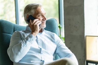 Akıllı telefonlu bir iş adamı ofisinden cep telefonuyla arıyor. Beyaz adam ofis lobisinde oturuyor. Arama yapmak için cep telefonu kullanıyor.