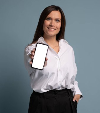 Akıllı telefon tutan iş kadını, mavi arkaplanda boş ekran gösteriyor