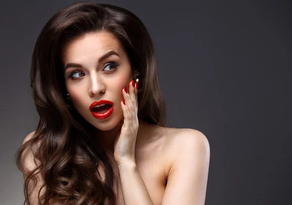 Modèle de beauté Femme avec de longs cheveux bruns ondulés. Cheveux sains et beau maquillage professionnel. Lèvres rouges et yeux fumés Maquillage. Superbe portrait de dame glamour. Soins capillaires, concept de soins de la peau — Photo