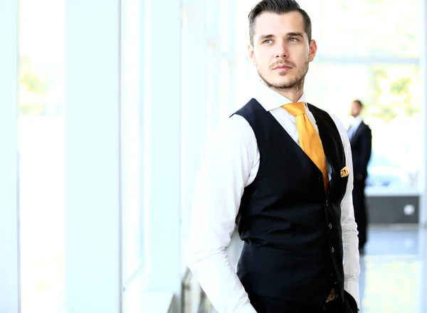 Happy young businessman in suit standing at office — Stock Photo, Image