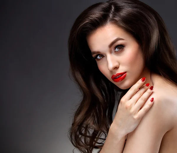 Женщина-модель красоты с длинными каштановыми волнистыми волосами. Красные губы и дымчатые глаза макияж. Уход за волосами, концепция Skincare — стоковое фото
