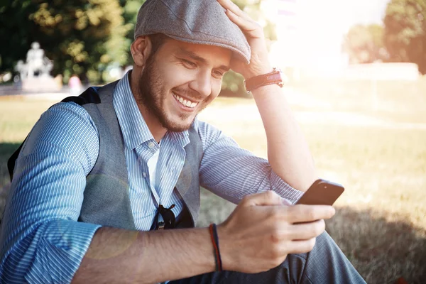 En ung forretningsmann på smarttelefon som går på gata med appen sms-melding på smarttelefon – stockfoto