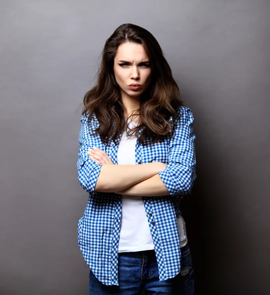 Портрет рассерженной женщины, стоящей со сложенными на сером фоне руками — стоковое фото