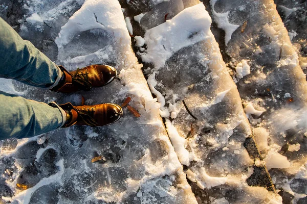 Danger of slipping. Female boots on rough slipper ice surface. A woman in brown leather shoes descends the slippery ice ladder — Stock Photo, Image