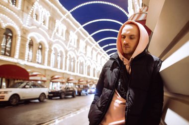 Yağmurlu sokağın arka planında kapüşonlu düşünceli bir adam..