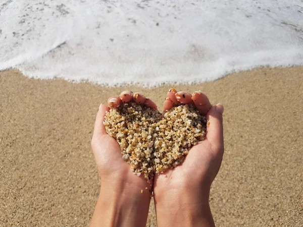 Corazón suave que forma las manos femeninas sobre el mar y la playa — Foto de Stock