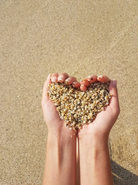 Мягкое сердце формирует женские руки над морем и пляжем — стоковое фото