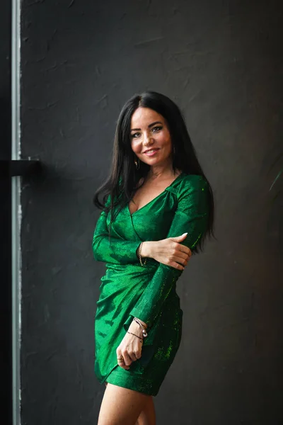 Sexy brunette vrouw in het kort groen jurk poseren op het donker interieur — Stockfoto