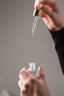 Gerekli yağ ve şişe damlasıyla Pipette hafif arka planda kadın ellerinde