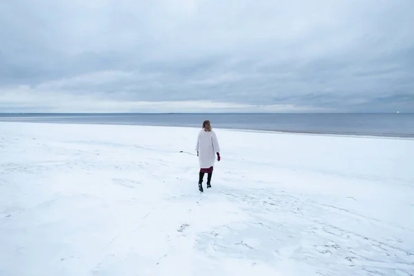 逃避现实，自然放松观念。寂寞的女孩穿着外套,背景是冬季的大海.一个女人在海上的画像，多风的天气，冰冷的大气形象 — 图库照片