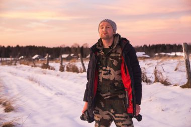 Kameralı adam renkli bir kış günbatımının tadını çıkarıyor ve kuzey doğası üzerine meditasyon yapıyor. Gökyüzünde güzel sirrus bulutları var.