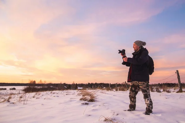 Male amateur photographer takes pictures of colorful winter sunset. Winter wonderland with purple colors — Stock Photo, Image