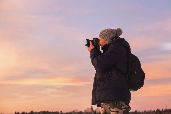 Мужчина-фотограф-любитель фотографирует красочный зимний закат. Зимняя страна чудес с фиолетовыми цветами — стоковое фото