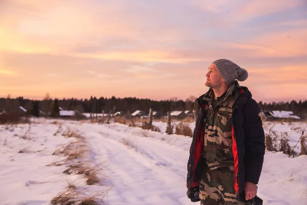 Mann mit Kamera genießt einen farbenfrohen Wintersonnenuntergang und meditiert über die nördliche Natur. Es gibt schöne Zirruswolken am Himmel — Stockfoto