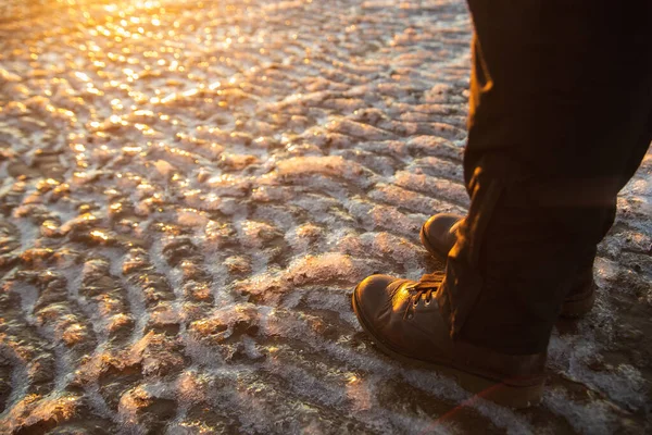 Nadchodzi zima. Damskie buty na szorstkiej pokrywie lodowej. Kobieta w brązowych skórzanych butach spacerująca po zimowym wybrzeżu morza — Zdjęcie stockowe