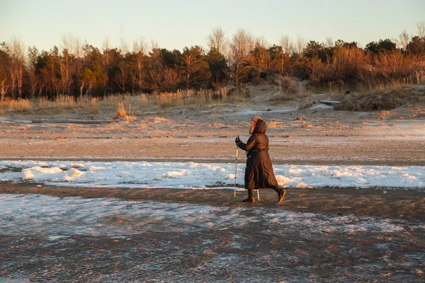 Sport d'hiver dans le nord - marche nordique. Femme âgée randonnée en hiver plage de la mer. Des gens actifs à l'extérieur. Paysage de coucher de soleil paisible — Photo