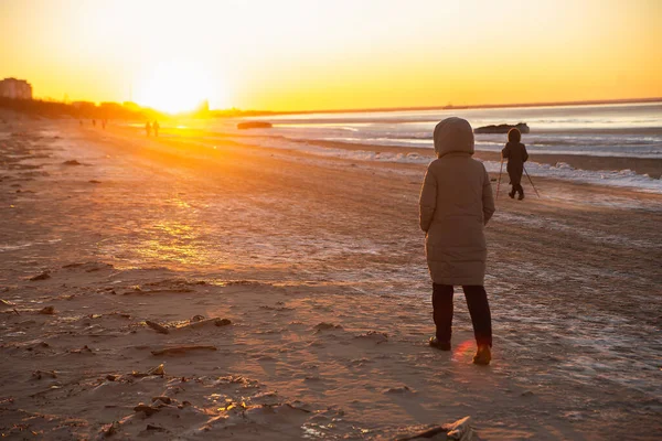 Paisaje invernal en playa, costa con hielo agrietado y agua de mar abierta. Caminando personas. — Foto de Stock