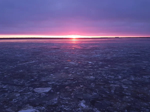 Rzeka z pękniętymi kryształami lodu w kolorowym mroźnym zachodzie słońca w fioletowych i różowych kolorach — Zdjęcie stockowe