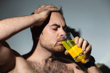 Yakın plan Latin adam dokunulmazlık için sarı renkli C vitamini içiyor.