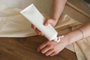 Kapalı eller ahşap arka plana bir damla kozmetik losyon sürerler..